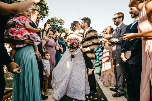 Newlywed couple sharing a kiss while surrounded by wedding guests