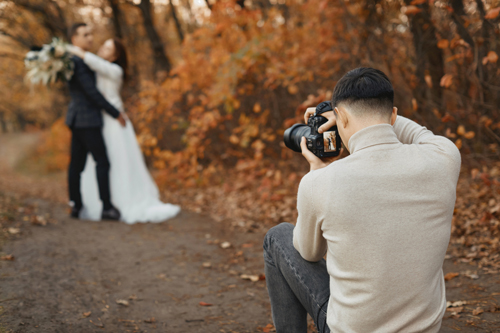 A wedding photographer capturing a couple during their autumn wedding.