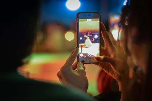 Person recording a wedding couple’s first dance with their cellphone