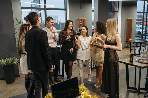 A group of stylish people clinking their glasses together in celebration at a company event.