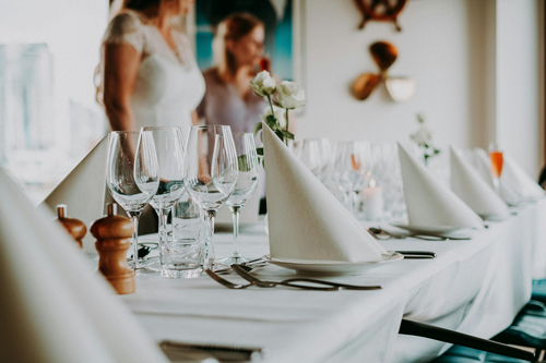A wedding table set with plates and glasses for many guests. Wedding food and catering are examples of wedding costs that can be inflated.
